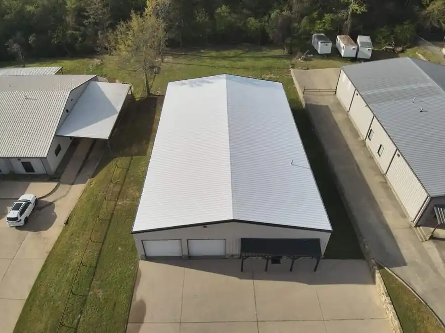 Drone view of a long metal commercial building with a fresh white roof coating