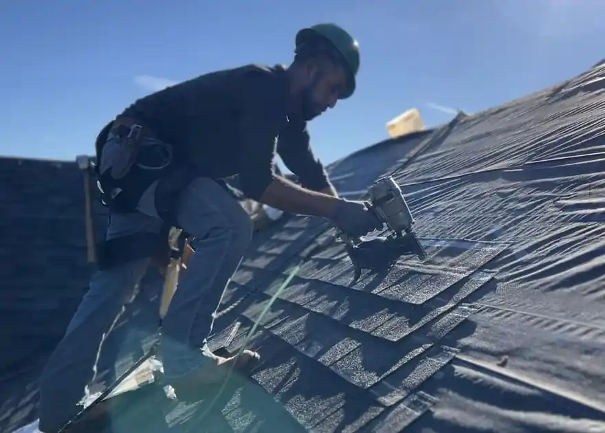 A roofer nailing synthetic underlayment to the decking