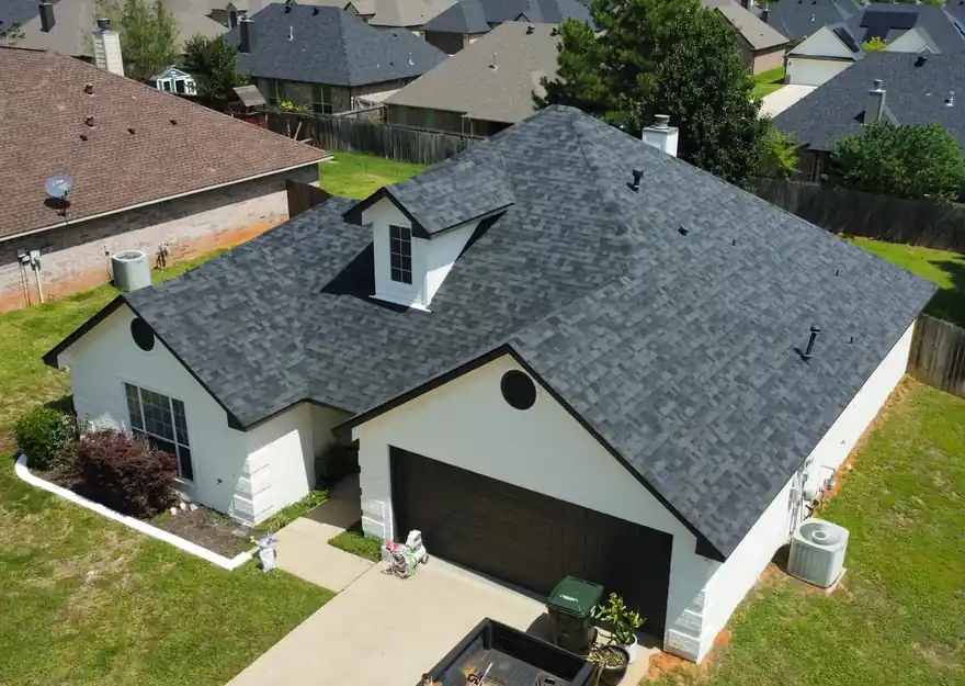 New charcoal architectural shingle roof on a white brick home, seen from a drone