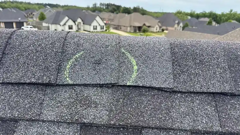 A ridge cap marked with chalk rings where hail struck, rooftops of a Tyler neighbourhood behind