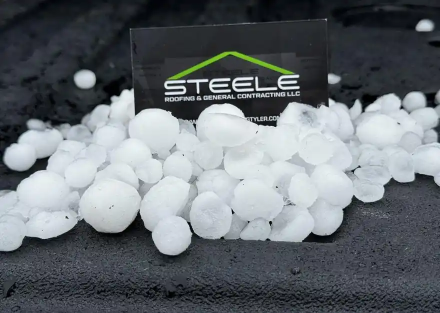 A pile of hailstones in front of a Steele Roofing business card after a storm in Whitehouse